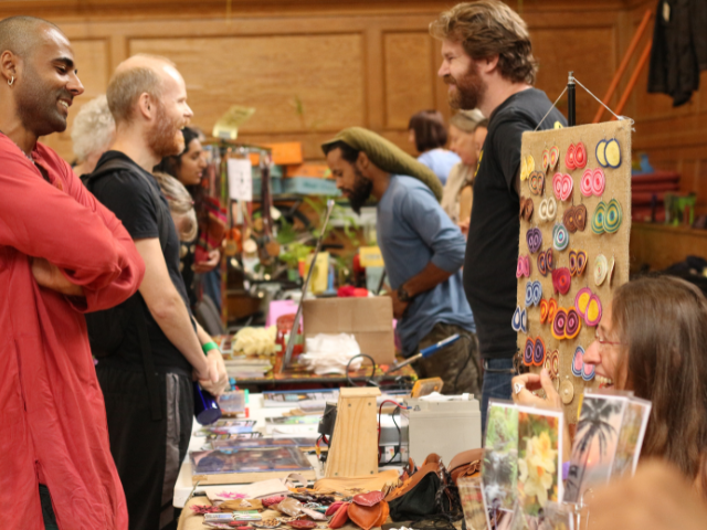 People gathering around a market stall smiling and having a conversation with the stall holder