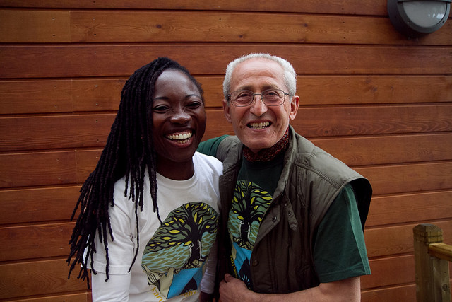 Two members at a convergence smile for the camera. They are wearing t-shirts designed by Karuna Insight Design.